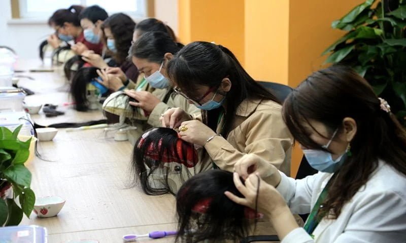 Skilled artisans hand-knotting wigs in factory