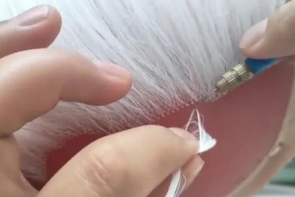 Hand-tying a hair topper to show the intricate craftsmanship