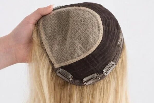 A close-up of a high-quality human hair topper showing a natural-looking scalp