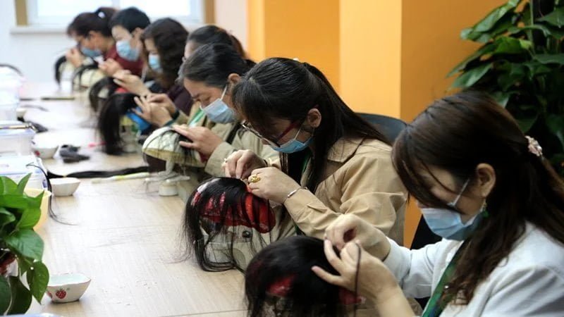 Experienced workers hand-ventilating lace wigs with precision